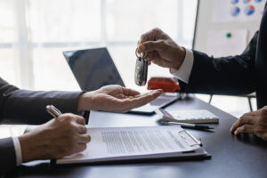 Truck dealer hands keys to customer, closing car insurance documents or rental agreement or agreement. Buying or selling a new car, close-up photo