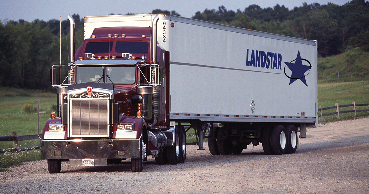 Flatbed owner-operator beside a tractor and flatbed trailer